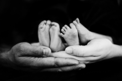 Two pairs of tiny feet belonging to twins held by their parents 